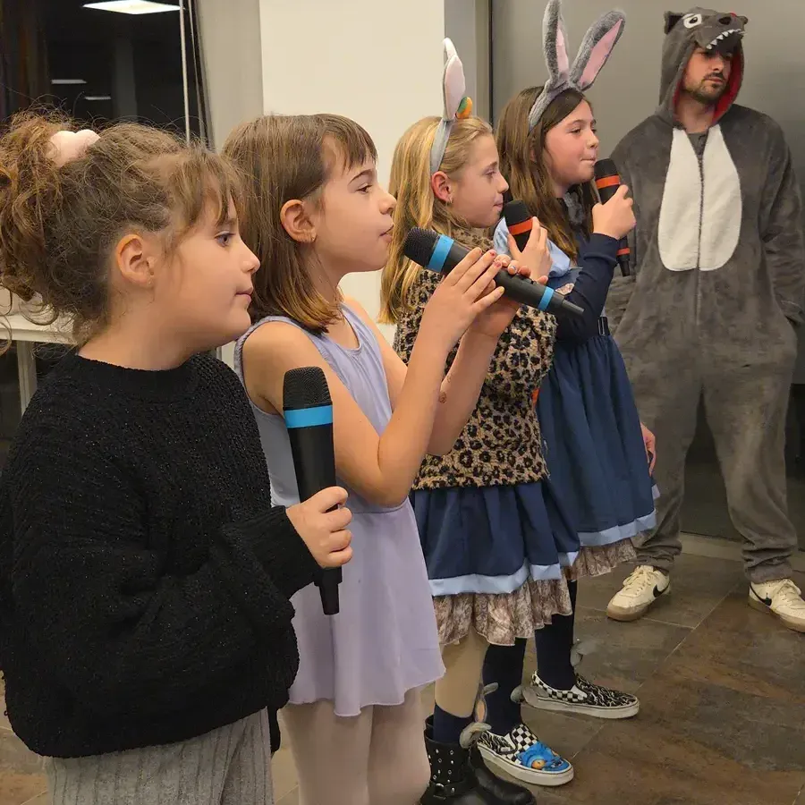 Alumnes cantant amb micròfons al costat d'un professor disfressat de llop